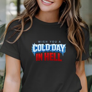 Puede incluir: Camiseta negra con la frase "WISH YOU A COLD DAY IN HELL" en letras blancas, azules y rojas. La tipografía tiene un diseño helado. Una prenda de vestir informal.