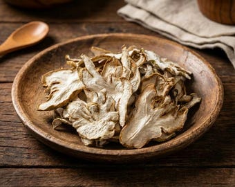 Può includere: Una ciotola di legno piena di funghi secchi di colore chiaro. I funghi hanno un aspetto strutturato e stratificato e sono disposti a cerchio. La ciotola è appoggiata su una superficie di legno rustica, con un cucchiaio di legno e un panno di lino sullo sfondo.