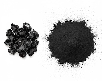May include: A top-down view of two distinct piles on a white background. One pile consists of irregularly shaped, glossy black pieces. The other is a mound of fine, black powder, with a few particles scattered around.