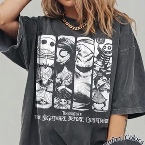 Peut inclure: Un t-shirt gris anthracite oversize avec une impression graphique blanche repr&eacute;sentant des personnages de Tim Burton's The Nightmare Before Christmas. Le motif comporte quatre panneaux verticaux avec diverses figures et le texte Tim Burton's The Nightmare Before Christmas. Une &eacute;tiquette Comfort Colors Pepper est visible dans le coin inf&eacute;rieur.
