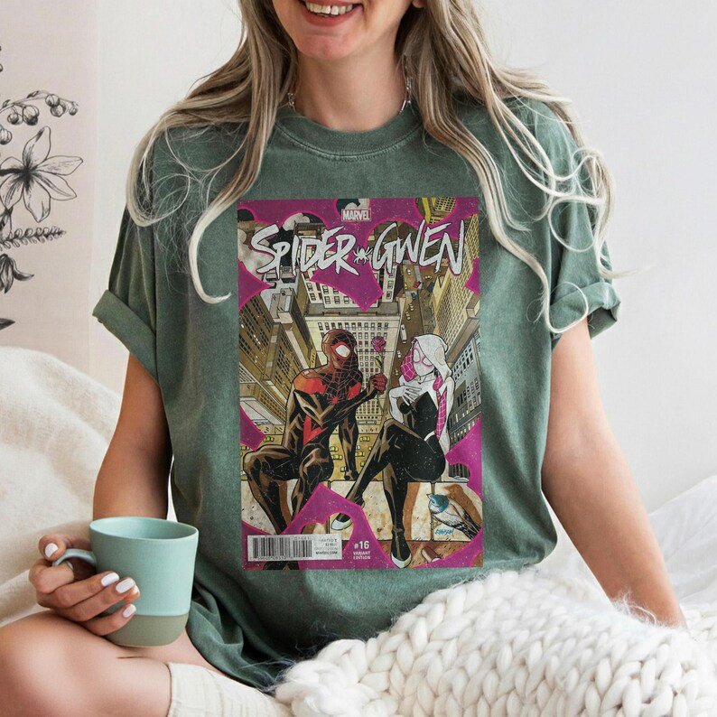 Puede incluir: Camiseta verde con una portada de c&oacute;mic de "Spider-Gwen". El arte del c&oacute;mic muestra a dos Spider-People en un entorno urbano. La camiseta tiene mangas cortas y cuello redondo.