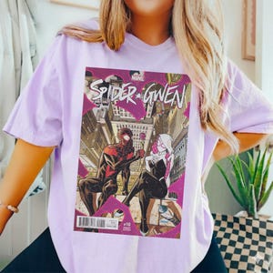 Puede incluir: Camiseta lila claro con una portada de c&oacute;mic de "Spider-Gwen". El arte del c&oacute;mic muestra a dos superh&eacute;roes disfrazados en un entorno urbano. El logotipo de Marvel es visible.