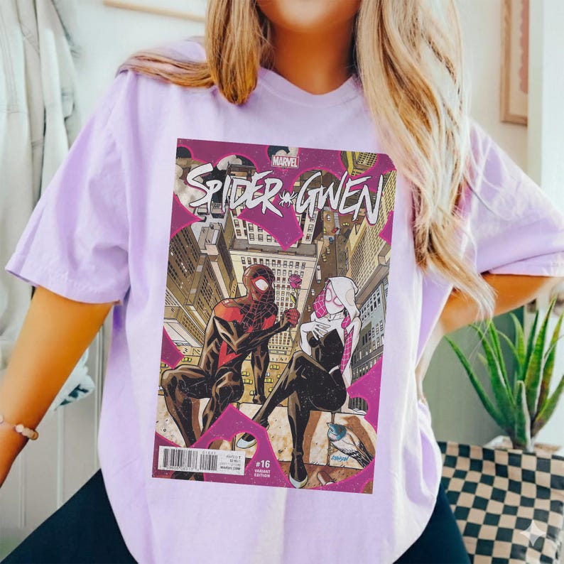 Puede incluir: Camiseta lila claro con una portada de c&oacute;mic de "Spider-Gwen". El arte del c&oacute;mic muestra a dos superh&eacute;roes disfrazados en un entorno urbano. El logotipo de Marvel es visible.