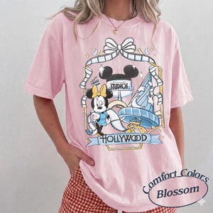 May include: A white ceramic mug with a black handle and the text "But First, Coffee" in a black, handwritten-style font. The mug is on a white surface.