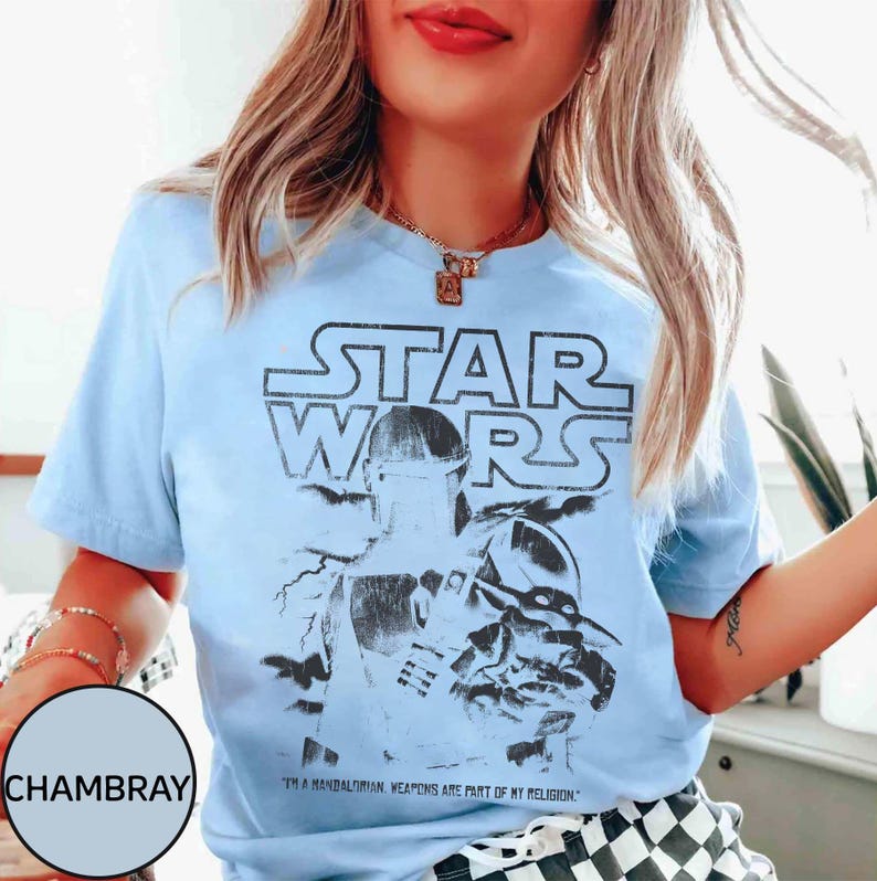 Puede incluir: Camiseta azul claro con un gr&aacute;fico de Star Wars con The Mandalorian. El dise&ntilde;o incluye el logotipo de Star Wars y el texto "I'm a Mandalorian. Weapons are part of my religion."