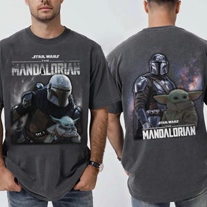 Puede incluir: Camiseta gris oscuro con el Mandaloriano y Grogu de Star Wars. El gr&aacute;fico frontal muestra al Mandaloriano y a Grogu, mientras que la parte posterior muestra al Mandaloriano y a Grogu con el texto "STAR WARS THE MANDALORIAN".