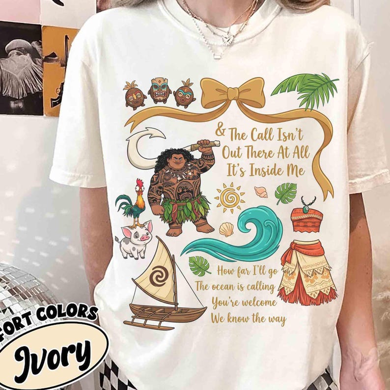 May include: Ivory-colored t-shirt featuring a colorful graphic design with the text "& The Call Isn't Out There At All It's Inside Me". The design includes illustrations of a boat, characters, and tropical elements.