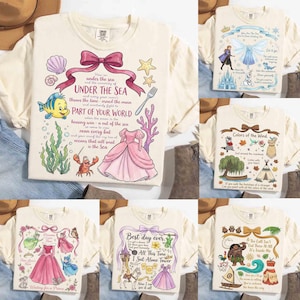 May include: Cream-colored graphic t-shirts featuring various Disney-themed designs. One shirt has the text "Under the Sea" with illustrations of a dress, fish, and coral. Other shirts display "Colors of the Wind", "Best day ever", and other quotes.