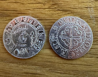 May include: Two silver coins with intricate designs. One coin features a profile of a crowned figure and text around the edge. The other coin displays a cross design with text around the edge. Both coins have a detailed, aged appearance.