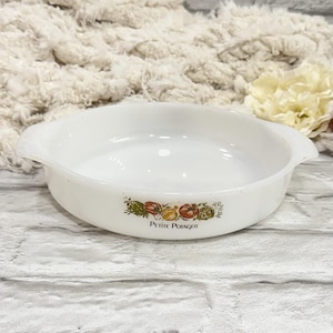 May include: White, round casserole dish with two handles. The dish features a colorful vegetable design with the text "PETITE POTAGER" in black. The dish is made of a glossy, opaque material.