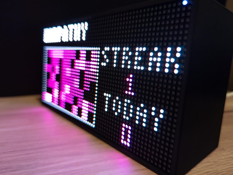 K&ouml;nnte beinhalten: Eine wei&szlig;e Keramik-Tasse mit schwarzem Henkel und dem Text "But First, Coffee" in fetter, schwarzer Schrift. Die Tasse steht vor einem verschwommenen Hintergrund, der eine gem&uuml;tliche Umgebung suggeriert.