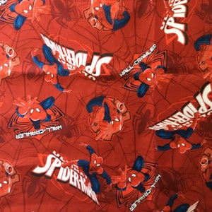 May include: Red fabric with a repeating pattern of Spiderman in various poses. The fabric features the words "Spider-Man" and "Wall-Crawler" in white lettering.