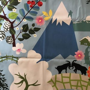 May include: A blue and white fabric with a mountain, trees, flowers, and two goats on a bridge. The fabric has a repeating pattern.