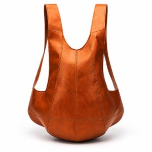 May include: A tan-coloured backpack with a smooth, structured surface and a unique, curved silhouette. The bag features vertical and horizontal stitched seams, two integrated shoulder straps, and a wide, rounded base that tapers towards the top.
