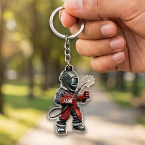 May include: A keychain featuring a cartoon welder in a welding helmet and red work clothes. The keychain has a silver ring and chain. The name "JASON" is printed on the welder's chest.