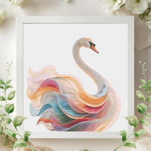 May include: A framed cross-stitch artwork featuring a swan with a curved neck and colorful plumage. The swan's feathers display shades of pink, orange, blue, and yellow. The artwork is set against a white background and framed in a white square frame.