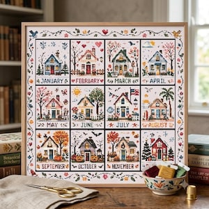 Könnte beinhalten: Ein gerahmtes Kreuzstichbild mit zwölf saisonalen Hausillustrationen, die jeweils mit einem Monat von Januar bis November beschriftet sind. Das Design zeigt bunte Motive von Bäumen, Blumen, Kürbissen und festlichen Elementen, umrandet von einer Blumenranke.