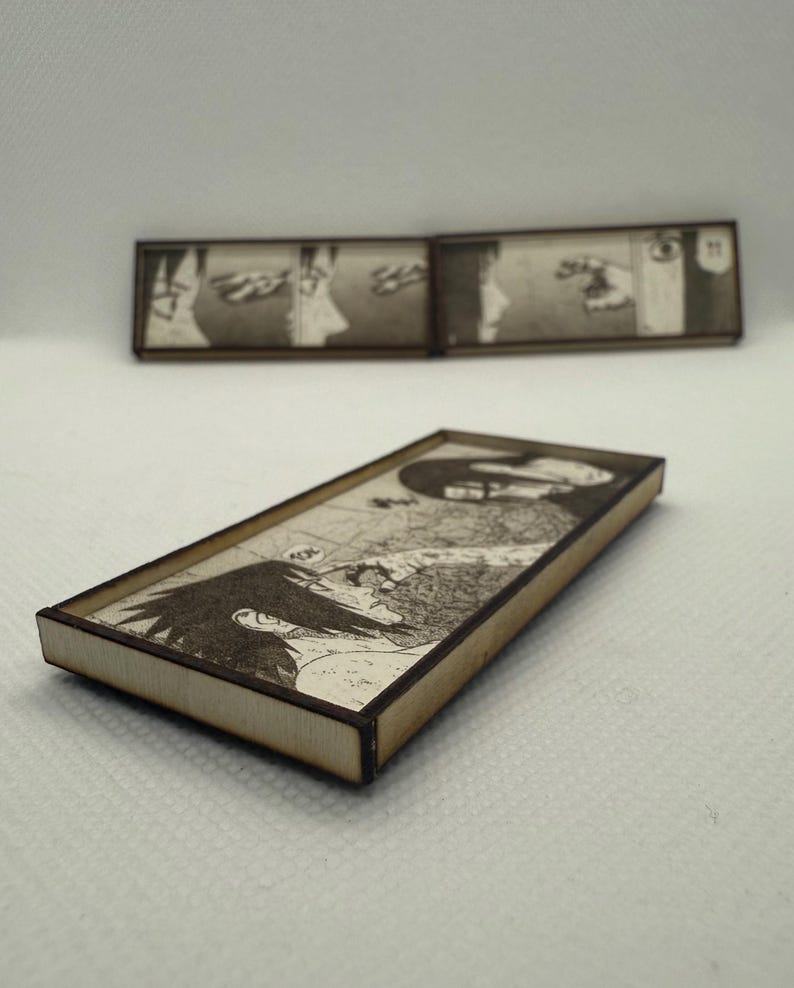 Peut inclure: Pi&egrave;ces d'art rectangulaires en bois avec des illustrations de manga en noir et blanc. L'&oelig;uvre est encadr&eacute;e d'une bordure marron clair. Une pi&egrave;ce est mise au point, tandis qu'une autre est en arri&egrave;re-plan. Les panneaux de manga repr&eacute;sentent une sc&egrave;ne dramatique.