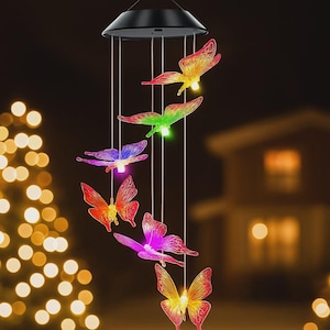 May include: A solar-powered wind chime featuring six colorful, illuminated butterfly ornaments. The butterflies are in shades of red, orange, green, purple, and yellow. The wind chime hangs from a black circular top, creating a decorative outdoor accent.