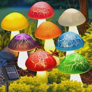 May include: A collection of solar-powered mushroom-shaped garden lights in various colors, including red, yellow, purple, orange, blue, green, and white. Each mushroom has a textured cap and a white stem, with a solar panel in the foreground.