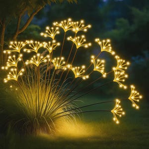 Op de afbeelding: Een cluster van decoratieve buitenverlichting in de vorm van sterrenbloemen. De warme gele lichten zijn gerangschikt op dunne, donkere stelen, die oprijzen uit een bed van hoog gras. De achtergrond is donkergroen, wat een nachtelijke setting suggereert.