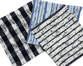 May include: Three woven fabric squares in a close-up shot. One features a black and white checkered pattern, another has blue and white stripes, and the third has black and white wavy stripes. The fabrics appear to be cotton or a similar material.