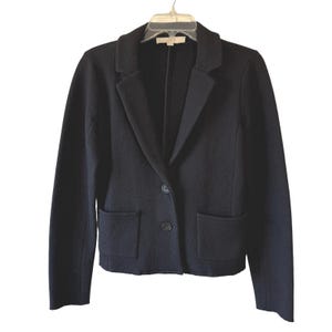 May include: A black blazer with a notched lapel, two front pockets, and a two-button closure. The jacket is hanging on a clear plastic hanger. The blazer is made of a wool blend.