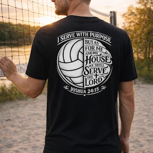 May include: Black t-shirt with a volleyball graphic and the text "I Serve With Purpose." The design includes the words "But as for me and my house, we shall serve the Lord, Joshua 24:15." The shirt is worn by a person near a volleyball net.