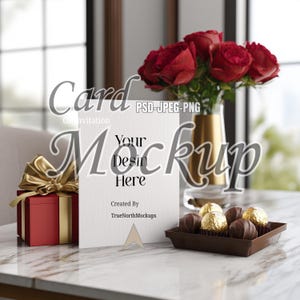 May include: A mockup of a card with the text "Your Design Here" on a marble table. A red gift box with a gold bow, a vase of red roses, and a tray of chocolates are also on the table. The card reads "Card Invitation Mockup".