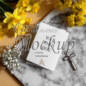 May include: A white card mockup with the text "Your Design Here" and "Card or Invitation" is surrounded by yellow daffodils, white baby's breath, and a silver cross on a marble surface. The card is created by TrueNorthMockups.