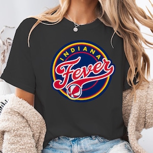 May include: Black t-shirt featuring the Indiana Fever logo. The logo is a circular design with the words "INDIANA" and "Fever" in red script, set against a blue background with yellow and red accents. A basketball graphic is also included.