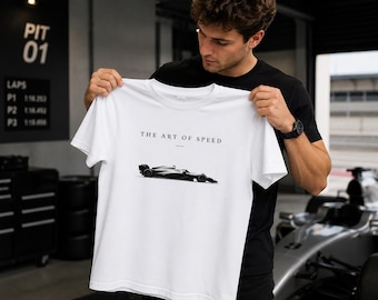 Könnte beinhalten: Ein weißes kurzärmeliges T-Shirt mit einer schwarz-weißen Grafik eines Formel-1-Rennwagens, die mittig auf der Brust platziert ist. Über dem Auto steht der Text THE ART OF SPEED in einer klaren, schwarzen, serifenlosen Schriftart.