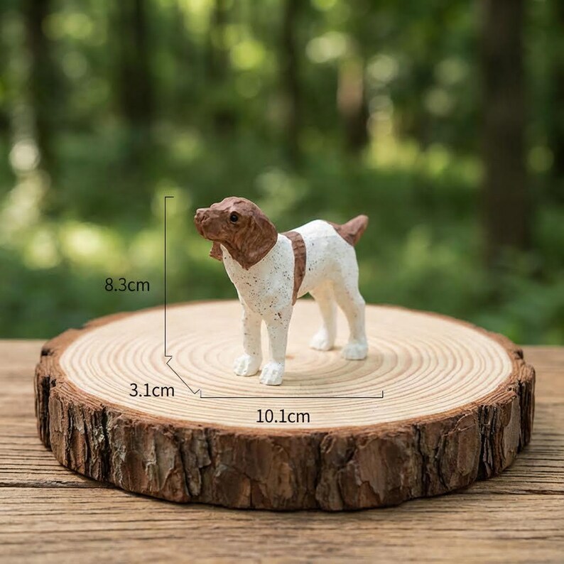 May include: A small, decorative dog figurine, primarily white with brown markings, stands on a round wooden slice. The figurine measures approximately 8.3 cm tall, with the wooden slice measuring 10.1 cm in diameter.