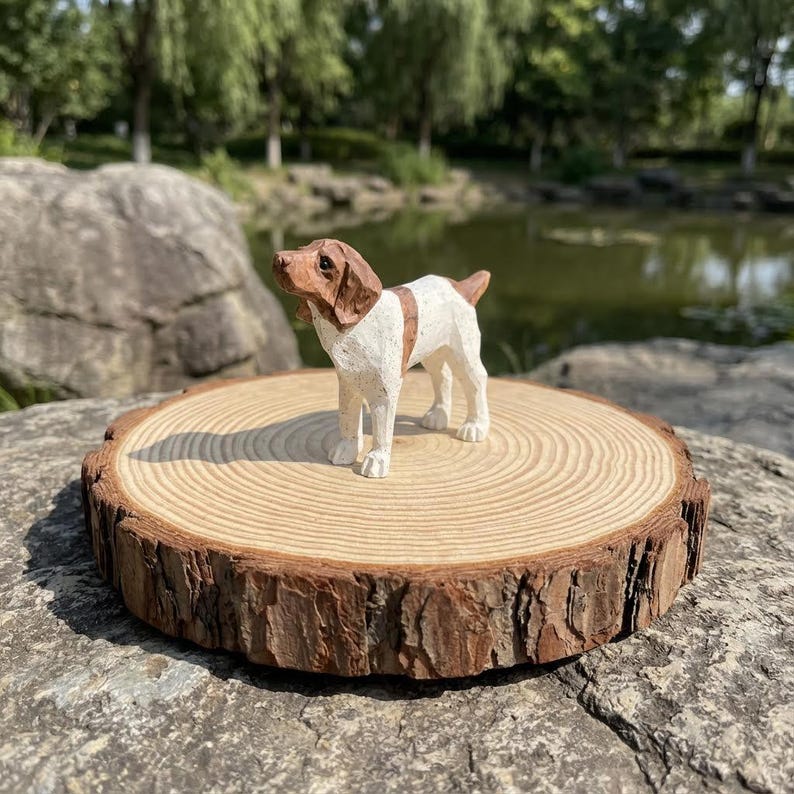 May include: A hand-carved wooden dog figurine, featuring a brown and white color scheme. The dog is standing on a round wooden slice with visible growth rings. The figurine has a detailed, textured appearance, and is set against a natural outdoor backdrop.