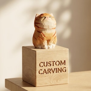 Pode incluir: Escultura em madeira de um gato com listras laranja e marrom, em cima de um bloco de madeira gravado com "CUSTOM CARVING". Esta figura de gato artesanal é um item decorativo único.