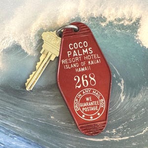 May include: A vintage red Coco Palms Resort Hotel key tag with a gold key. The tag reads "Coco Palms Resort Hotel Island of Kauai Hawaii 268" and "Drop in any mailbox, we guarantee postage."
