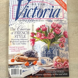 May include: A magazine cover featuring the title "Victoria" with a blue and white gingham pattern. The cover includes text about French style, a vase of pink tulips, a teacup, and croissants. The magazine is a special French issue.