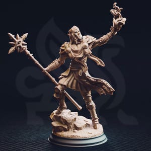 Può includere: Statuetta dettagliata di un personaggio fantasy, con in mano un bastone con una stella e una torcia fiammeggiante. La figura è vestita con un'armatura e si trova su una base rocciosa, con uno sfondo scuro.