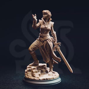 Könnte beinhalten: Detaillierte Figur einer Kriegerin in dynamischer Pose, die ein Schwert hält. Die Figur ist mit detaillierter Rüstung und Kleidung bekleidet und steht auf einem felsigen Sockel. Die Farbe ist ein warmes, helles Braun mit aufwendigen Details an Kleidung und Waffe.