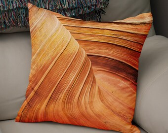 May include: A close-up of a pillow featuring a photograph of a sandstone formation with a swirling, layered pattern in shades of orange, brown, and yellow.