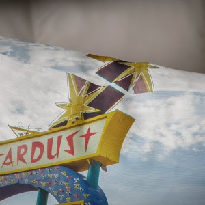May include: A vintage sign with a yellow background and red lettering that reads "ARDUST" with a red star on the sign. The sign is topped with two large, yellow, neon stars.