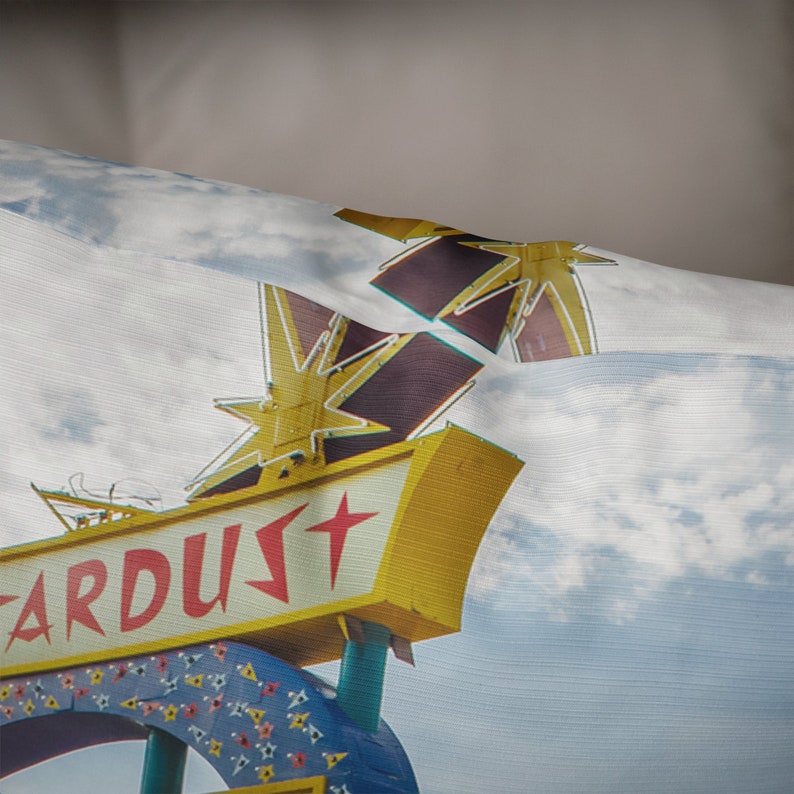 May include: A vintage sign with a yellow background and red lettering that reads "ARDUST" with a red star on the sign. The sign is topped with two large, yellow, neon stars.