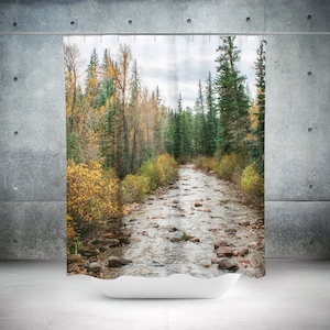 May include: A scenic shower curtain featuring a view of a stream flowing through a forest. The stream is surrounded by trees with yellow and green leaves, creating a vibrant autumnal scene.