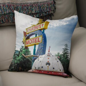 May include: A vintage motel sign with the words "Stardust Motel" in red and yellow letters on a blue background. The sign is attached to a large, white, dome-shaped structure that resembles a flying saucer.