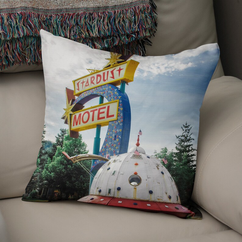May include: A vintage motel sign with the words "Stardust Motel" in red and yellow letters on a blue background. The sign is attached to a large, white, dome-shaped structure that resembles a flying saucer.