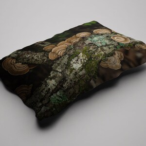 May include: A cushion with a detailed image of a tree branch covered in brown and tan bracket fungi. The branch has patches of green moss and lichen, set against a dark, blurred background. The cushion has a natural, earthy theme.