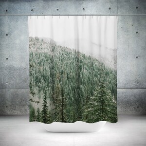 May include: A shower curtain featuring a scenic landscape of a snowy forest with tall evergreen trees. The trees are covered in a light dusting of snow, and the background is a hazy, white sky.