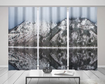 May include: A set of three window curtains featuring a snowy mountain landscape reflected in a still lake. The curtains are a light gray color and the mountains are a dark gray with white snow.