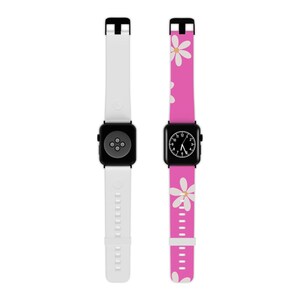 May include: Two smartwatches with black square faces and bands. One band is white, the other is pink with white daisy patterns. The watch faces display the time. The bands have a pin and hole closure.