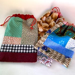 May include: Three patchwork drawstring bags in various sizes and patterns. One bag features green polka dots, floral prints, and a black and white checkered pattern. Another has a print of bread, and the third has blue and brown geometric designs.